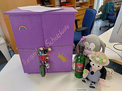 Eine Box mit vielen Schlössern. Daneben zwei Kuscheltiere.