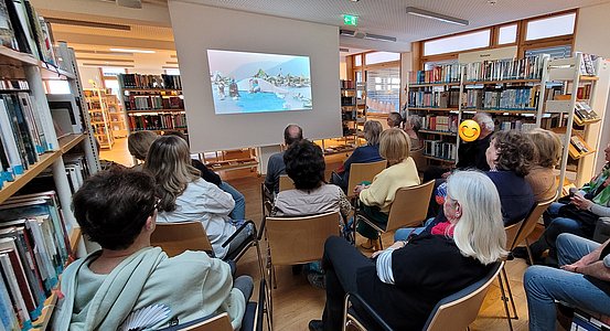 Publikum blickt auf eine Präsentationsleinwand