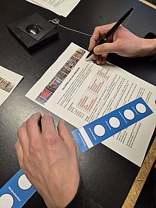 Draufsicht auf zwei Hände über einem Rätselpapier