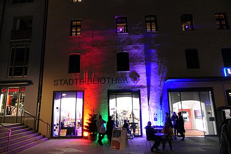 Die im dunklen bunt angestrahlte Außenfassade der Stadtbibliothek Rosenheim